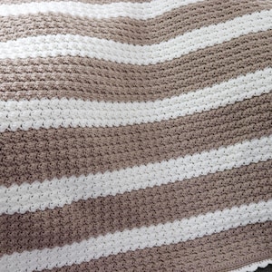 May include: A brown and white striped crocheted blanket with a scalloped edge.