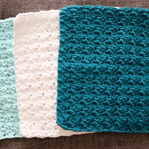 May include: Three crocheted dishcloths in different colors: light blue, white, and teal.