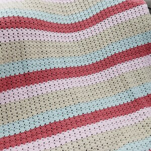 May include: A striped crocheted blanket in shades of pink, beige, blue, and red. The blanket is made with a textured stitch and has a wavy pattern.