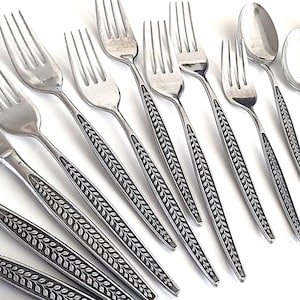 May include: A set of stainless steel silverware, including forks, knives, and spoons. The handles feature a leaf design. The silverware is arranged on a white surface.