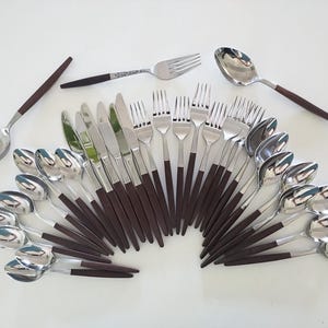 May include: A collection of stainless steel silverware with dark brown handles. The set includes spoons, forks, and knives, arranged in a fan shape. The silverware has a modern design, with a polished finish.