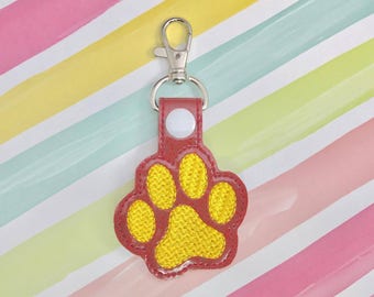 May include: Red and yellow paw print keychain with a silver metal clasp.