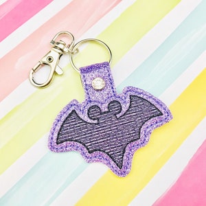 May include: Purple glitter bat-shaped keychain with a silver metal clasp.