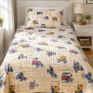 May include: A cream-colored quilt and pillow set featuring a repeating pattern of vintage cars in various colors. The cars are red, blue, yellow, and gray, with a detailed background of mechanical drawings.
