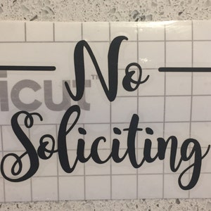 May include: Black vinyl sticker with the text "No Soliciting" in a cursive font.