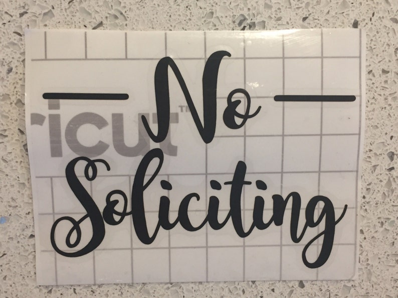 May include: Black vinyl sticker with the text "No Soliciting" in a cursive font.