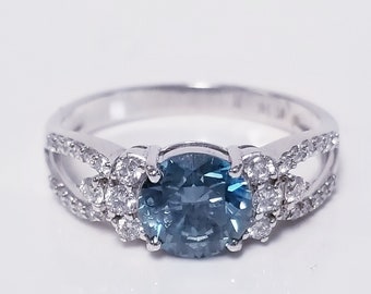 Könnte beinhalten: Ein silberner Ring mit einem blauen Edelstein, der von kleineren weißen Edelsteinen umgeben ist.