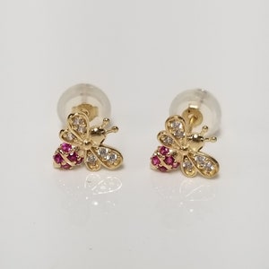 May include: A pair of gold bee stud earrings with pink and white cubic zirconia stones.