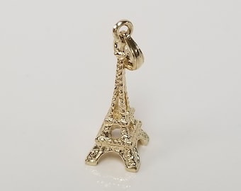 May include: A gold-colored Eiffel Tower charm pendant. The charm is detailed and has a loop at the top for attaching to a necklace or bracelet.