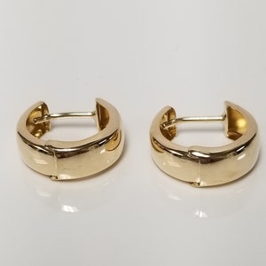 May include: A pair of gold hoop earrings. The earrings are smooth and have a polished finish.