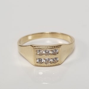 May include: A gold ring with a rectangular band and two rows of clear stones.