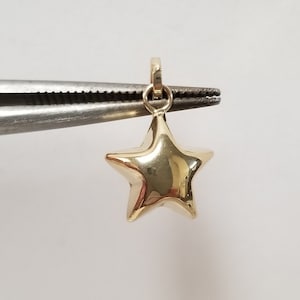 May include: A gold-colored star-shaped charm pendant with a loop at the top.