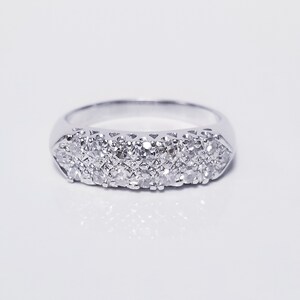 Op de afbeelding: Een zilveren bandring met een rij kleine diamanten die in de band zijn gezet.