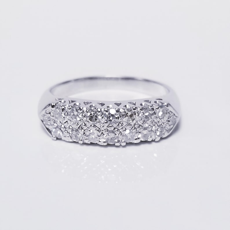 Op de afbeelding: Een zilveren bandring met een rij kleine diamanten die in de band zijn gezet.