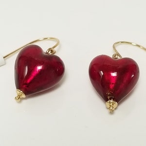 May include: A pair of red heart-shaped glass earrings with gold hooks and a gold bead at the bottom of each heart.