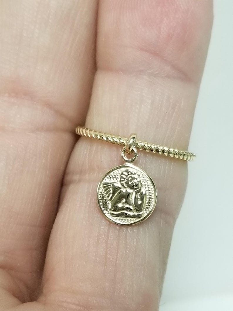May include: A gold ring with a twisted band and a small charm of an angel with wings.