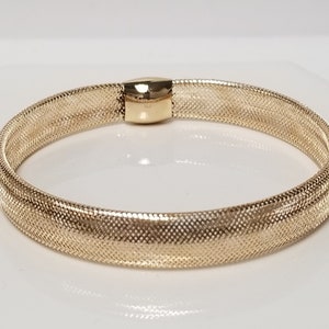 May include: A gold mesh bracelet with a clasp closure.
