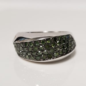 May include: A silver ring with a curved band set with green diamonds.