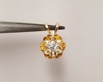 May include: A gold flower pendant with a clear round gemstone in the center. The pendant has a loop at the top for attaching to a chain.