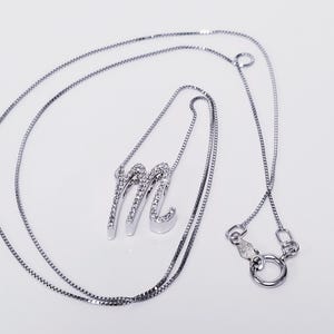 May include: A silver chain necklace with a diamond-encrusted letter M pendant.