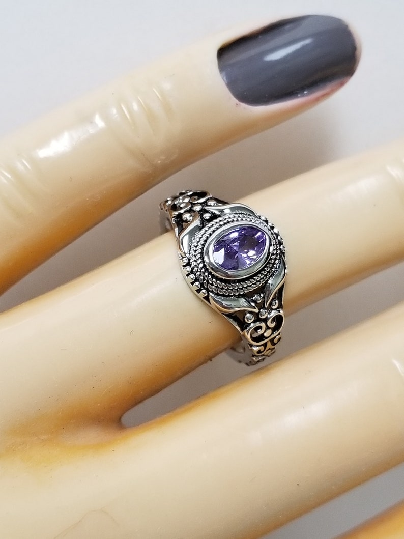 May include: A silver ring with an ornate design and a purple gemstone.
