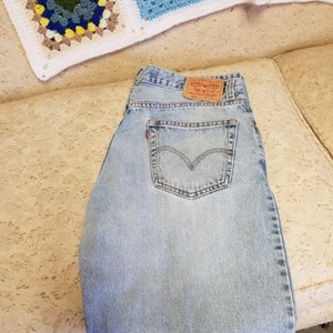 May include: Light blue denim jeans with a brown leather Levi's patch on the back pocket. The patch has the text "Levi Strauss & Co.", "San Francisco, Ca. 90102", "Original  Rivet", "Quality Clothing", and "W 32 L 32".