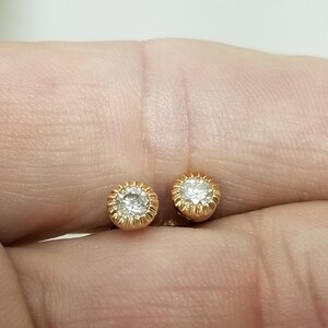May include: A pair of gold stud earrings with a small round diamond in the center of each earring.