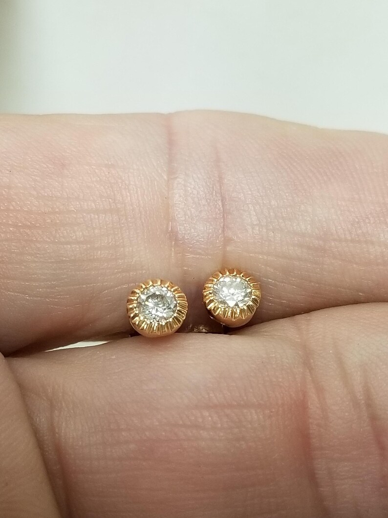 May include: A pair of gold stud earrings with a small round diamond in the center of each earring.