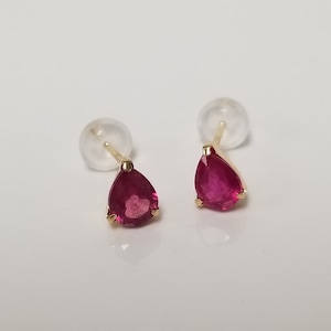 May include: A pair of gold earrings with red pear-shaped gemstones.