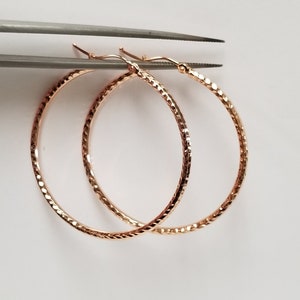 May include: A pair of gold-toned hoop earrings with a textured diamond pattern.