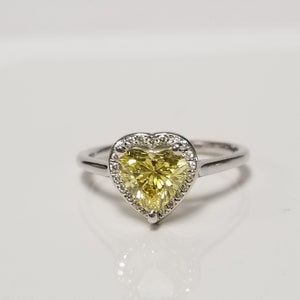 May include: A silver ring with a heart-shaped yellow gemstone surrounded by a halo of smaller diamonds.