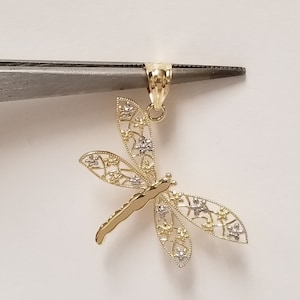 May include: A gold dragonfly pendant with intricate filigree details. The wings are made of two-toned gold, with a yellow gold center and white gold edges.