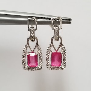 May include: A pair of silver earrings with pink rectangular gemstones set in a diamond-shaped frame.