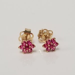 May include: A pair of gold flower-shaped stud earrings with pink gemstones.