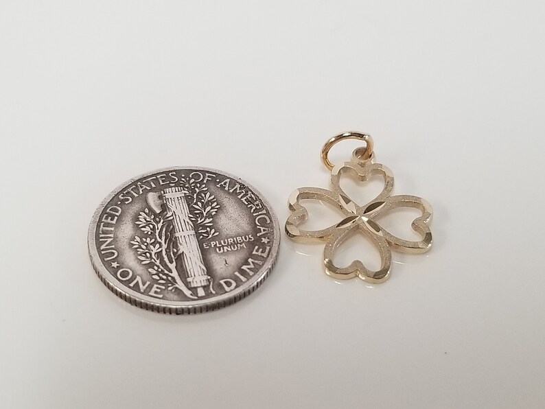 May include: A gold-colored four-leaf clover charm pendant. The charm is about the size of a US dime.