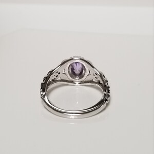 May include: A silver ring with an intricate design and a purple gemstone in the center.