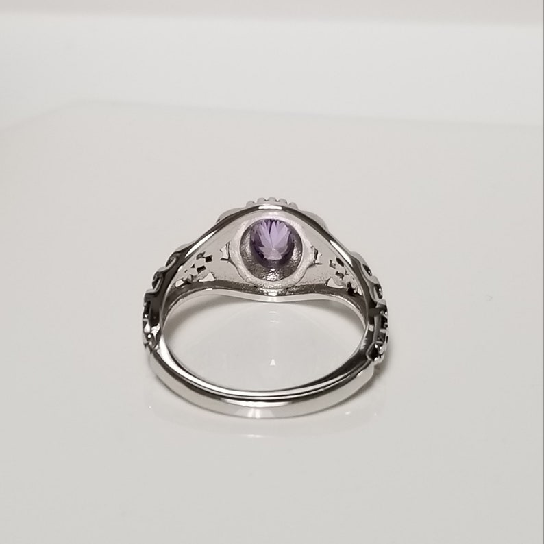 May include: A silver ring with an intricate design and a purple gemstone in the center.