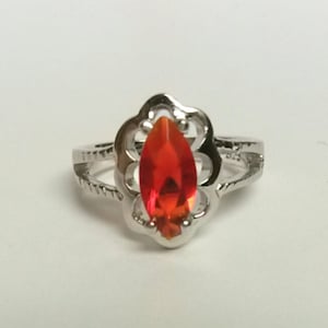 May include: A silver ring with a red gemstone set in a delicate floral design.