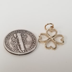 May include: A gold-colored four-leaf clover charm pendant. The charm is about the size of a US dime.
