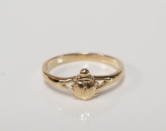 May include: A gold ring with a ladybug design. The ladybug is detailed with raised spots and a smooth, rounded body.