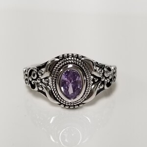 May include: A silver ring with an ornate design and a purple oval gemstone.
