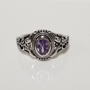 May include: A silver ring with an ornate design featuring a purple gemstone.