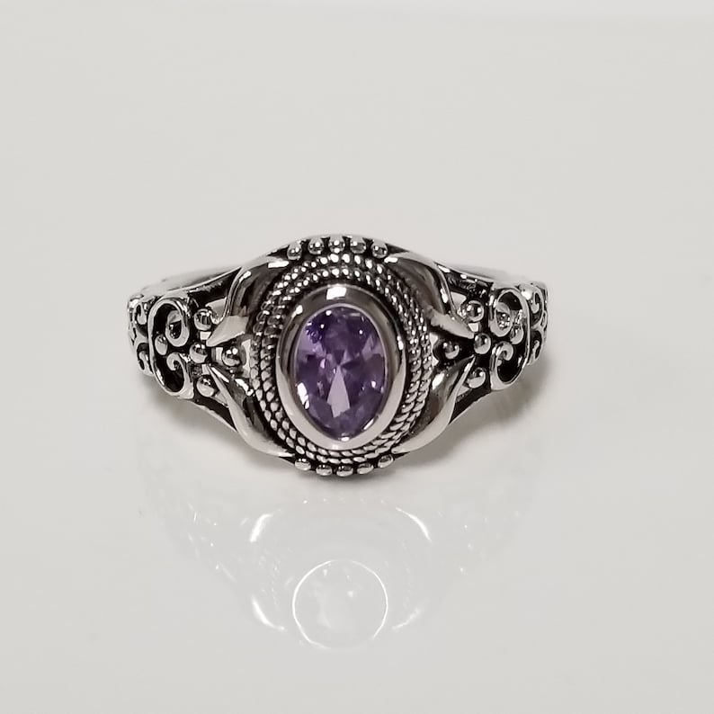 May include: A silver ring with an ornate design featuring a purple gemstone.