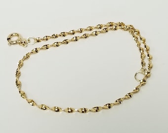 May include: A gold chain bracelet featuring a twisted, reflective link design. The bracelet is constructed with a circular spring ring clasp at one end and a small jump ring at the other, showcasing a polished, metallic finish throughout the piece.