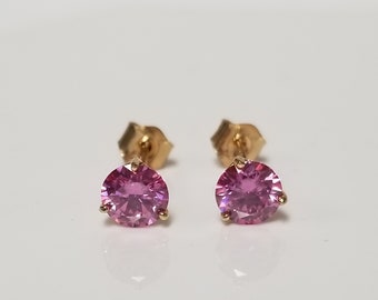 May include: A pair of gold stud earrings with pink round gemstones.