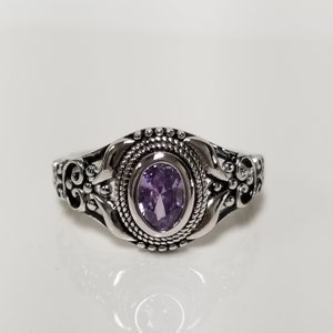 May include: A silver ring with an ornate design and a purple oval gemstone.
