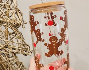 May include: A clear glass tumbler with a bamboo lid and a glass straw. The tumbler has a gingerbread man design with red dots.