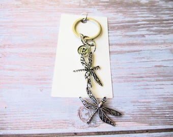 Libellen-Schlüsselanhänger und silberfarbener Initial-Charm an Karte mit Geschenkbeutel
