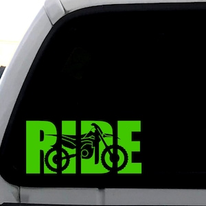 Puede incluir: Calcomanía de vinilo verde con la palabra "RIDE" en letras grandes. Una silueta de una moto de cross está incorporada en las letras.