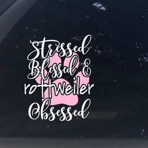 May include: White vinyl decal with the text "Stressed Blessed & Rottweiler Obsessed" with a pink paw print in the center.